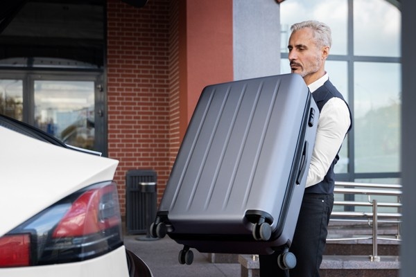 Man with suitcase next to car at Denver Airport ready to use Blue Shuttle Van